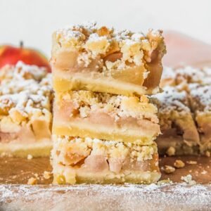 Shortbread apple bars sit stacked on parchment paper.