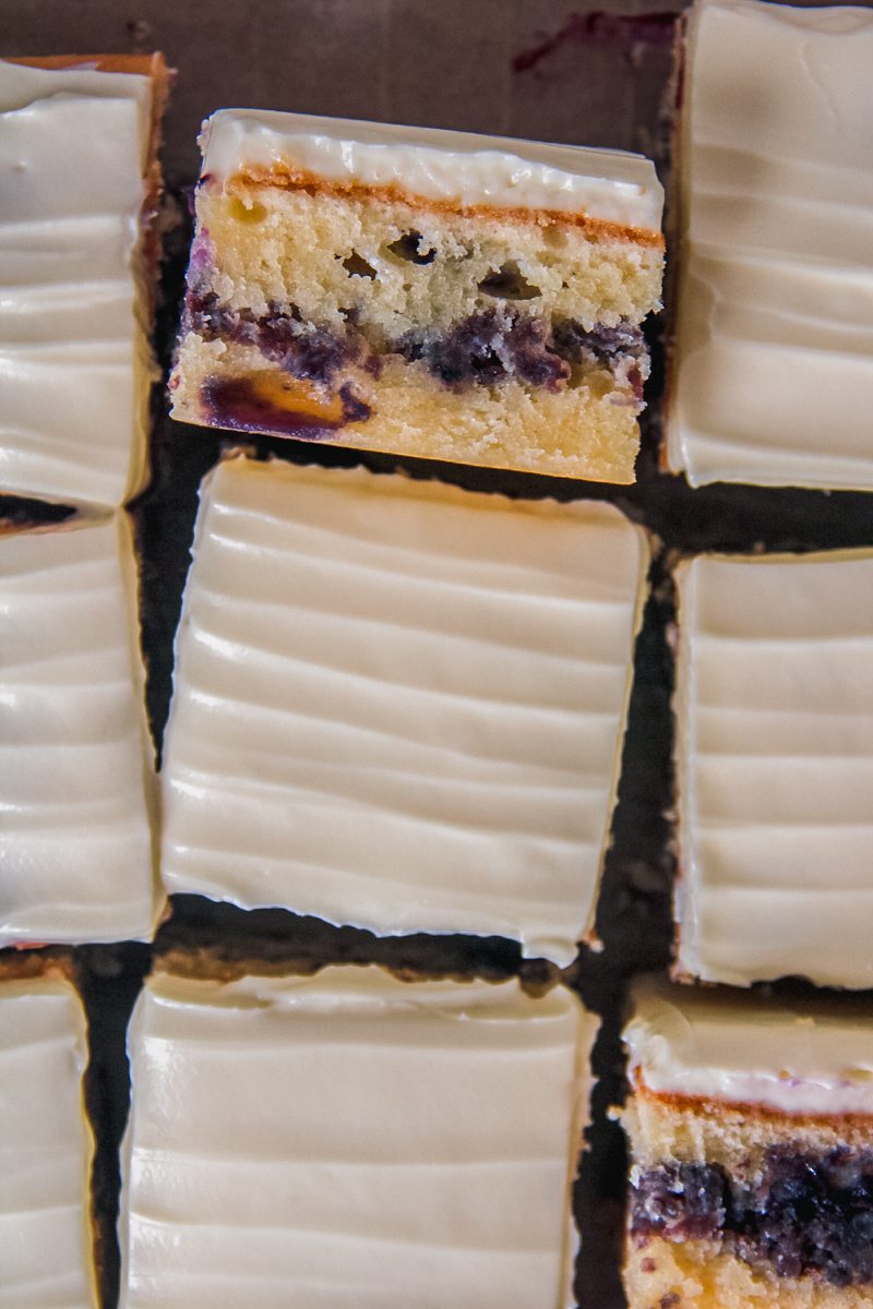 A slice of blueberry sheet cake sits on it's side with the line of homemade blueberry streusel center visible.