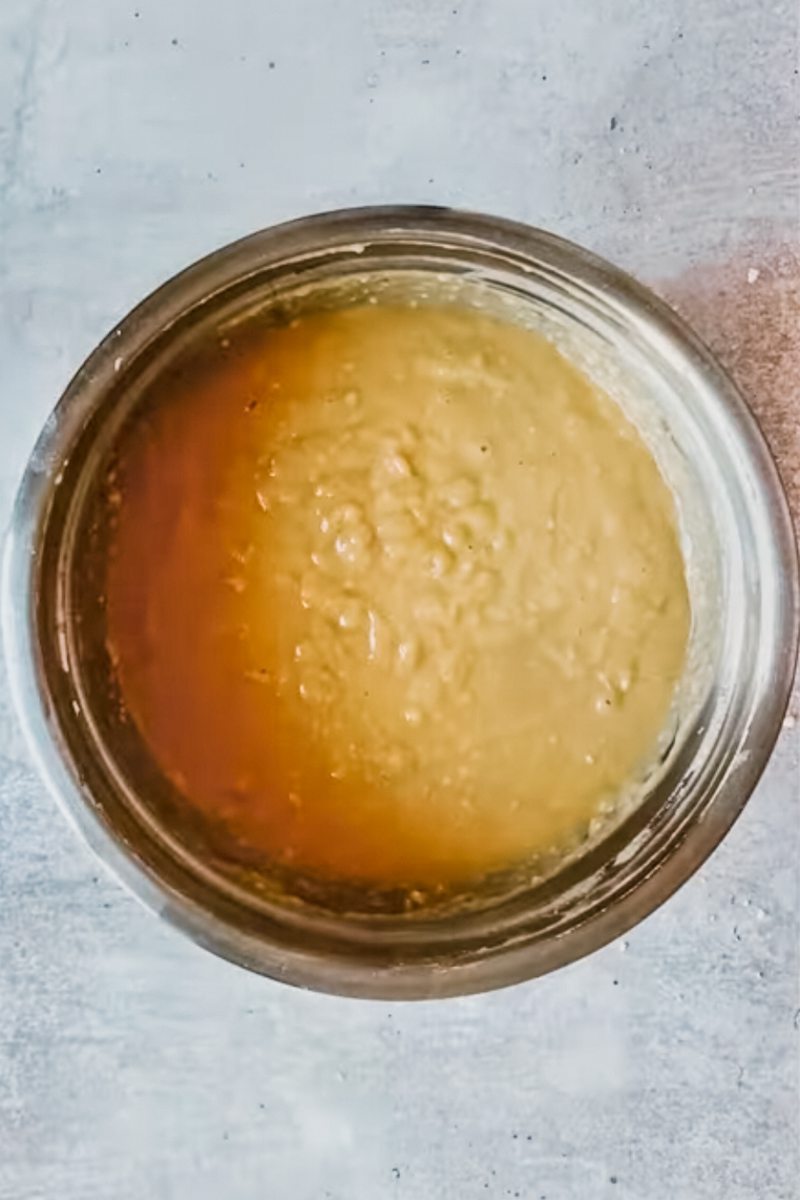 Burnt sugar steam pudding batter sits in a stainless steel bowl on a gray surface.