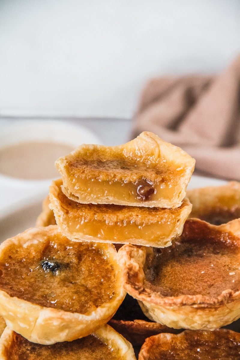 A halved butter tart sits on top of other butter tarts.