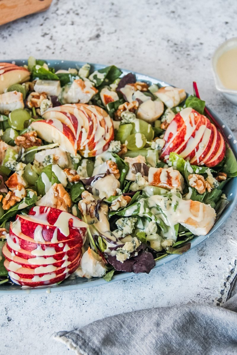 Side image of waldorf salad topped with dressing served on a gray surface.