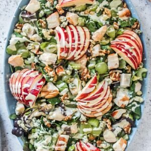 An overhead image of a Waldorf salad topped with dressing served on a gray surface.