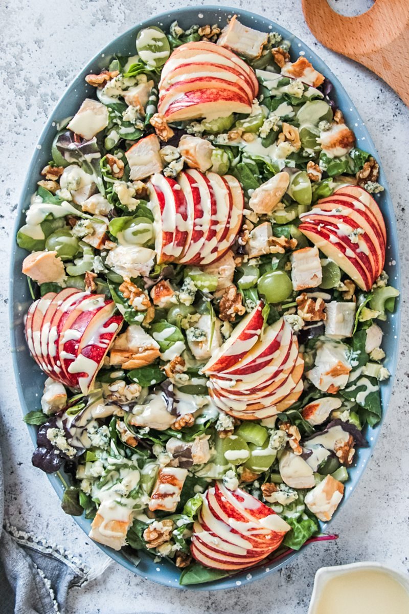 An overhead image of a Waldorf salad topped with dressing served on a gray surface.