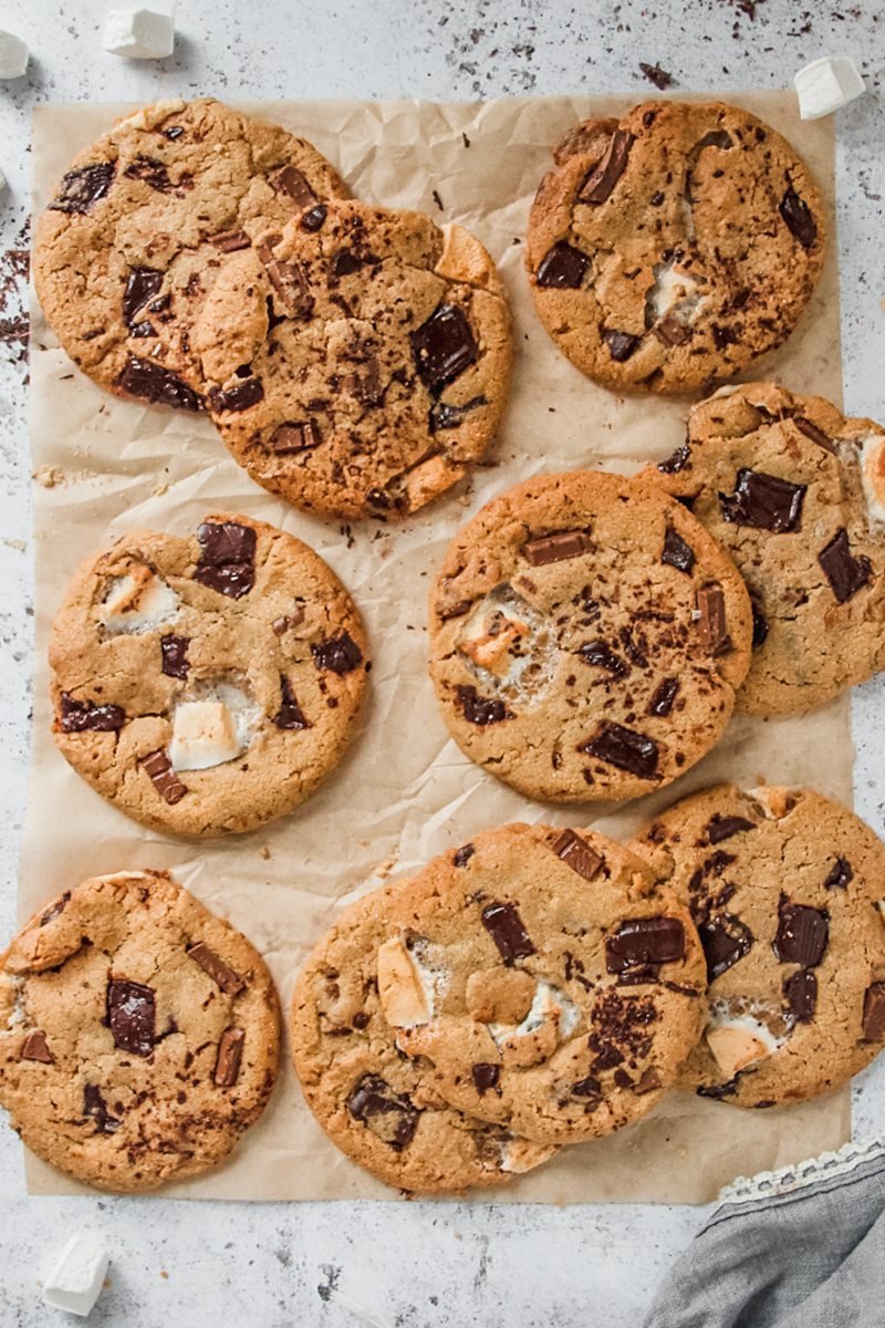 Smore cookies lay unevenly on each other on greaseproof paper on a light gray background.