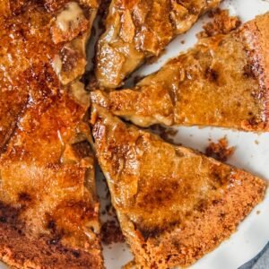 Coffee creme brulee custard pie sits in a white ceramic baking dish with a few slices cut out.