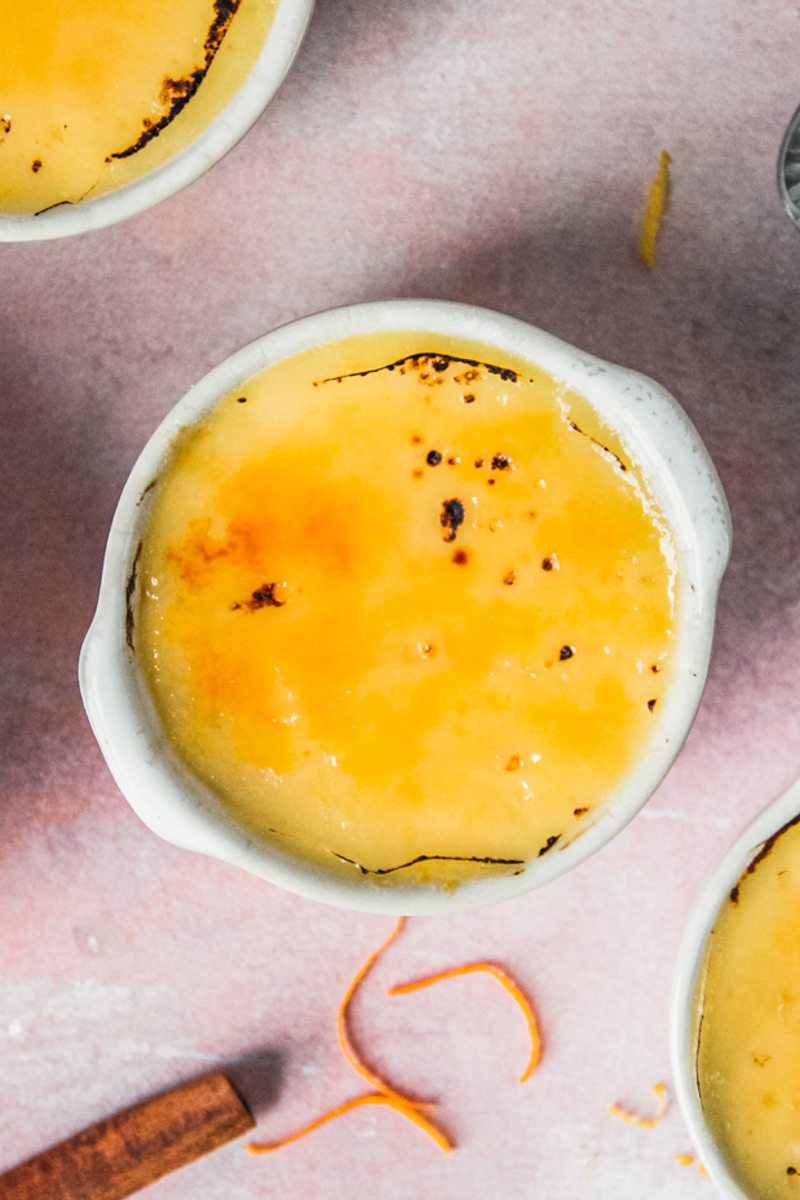 Crema Catalana with a caramelized topping sits on a light pink surface.