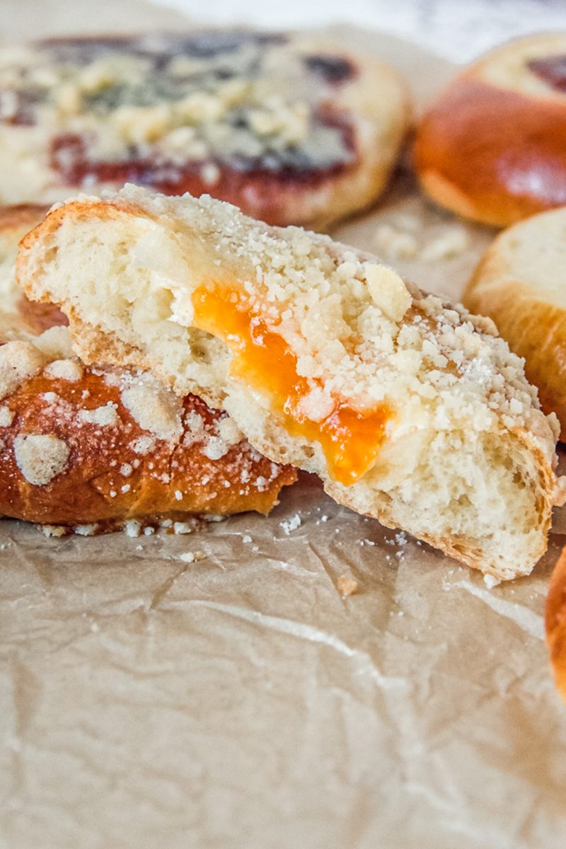 A halved kolache sits on parchment paper leaning on another kolache.