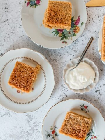 Slices of Danish dream sit served up on individual plates on a gray surface served beside a small plate of Greek yogurt.