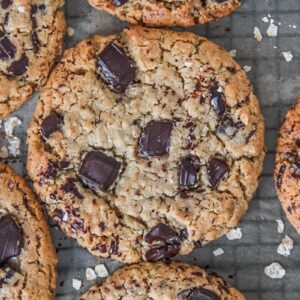 A close up of Tahini oatmeal chocolate chunk cookies sitting on a lined cooling rack.