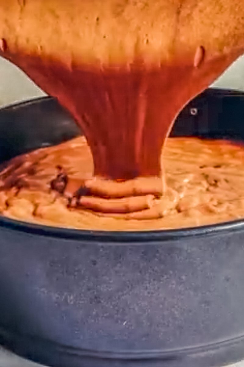 Flourless chocolate cake batter is poured into a cake tin.