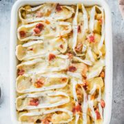 Tartiflette sits in a rectangle white ceramic baking dish on a gray surface.