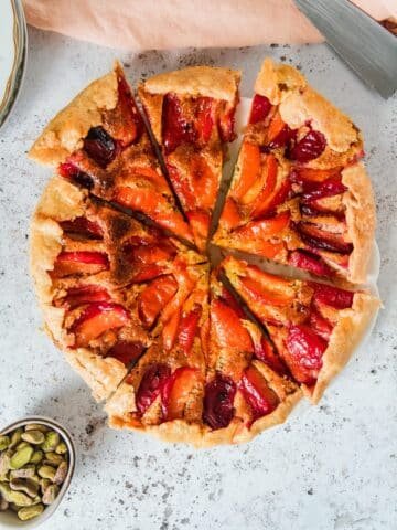 An apricot galette is sliced up and served on a light grey background.