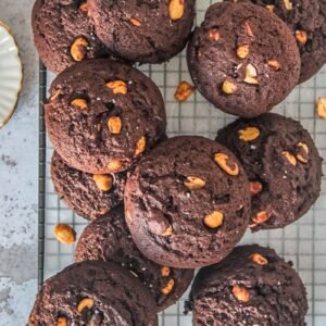 Peanut brownie cookies sit on a cooling rack on a gray surface.