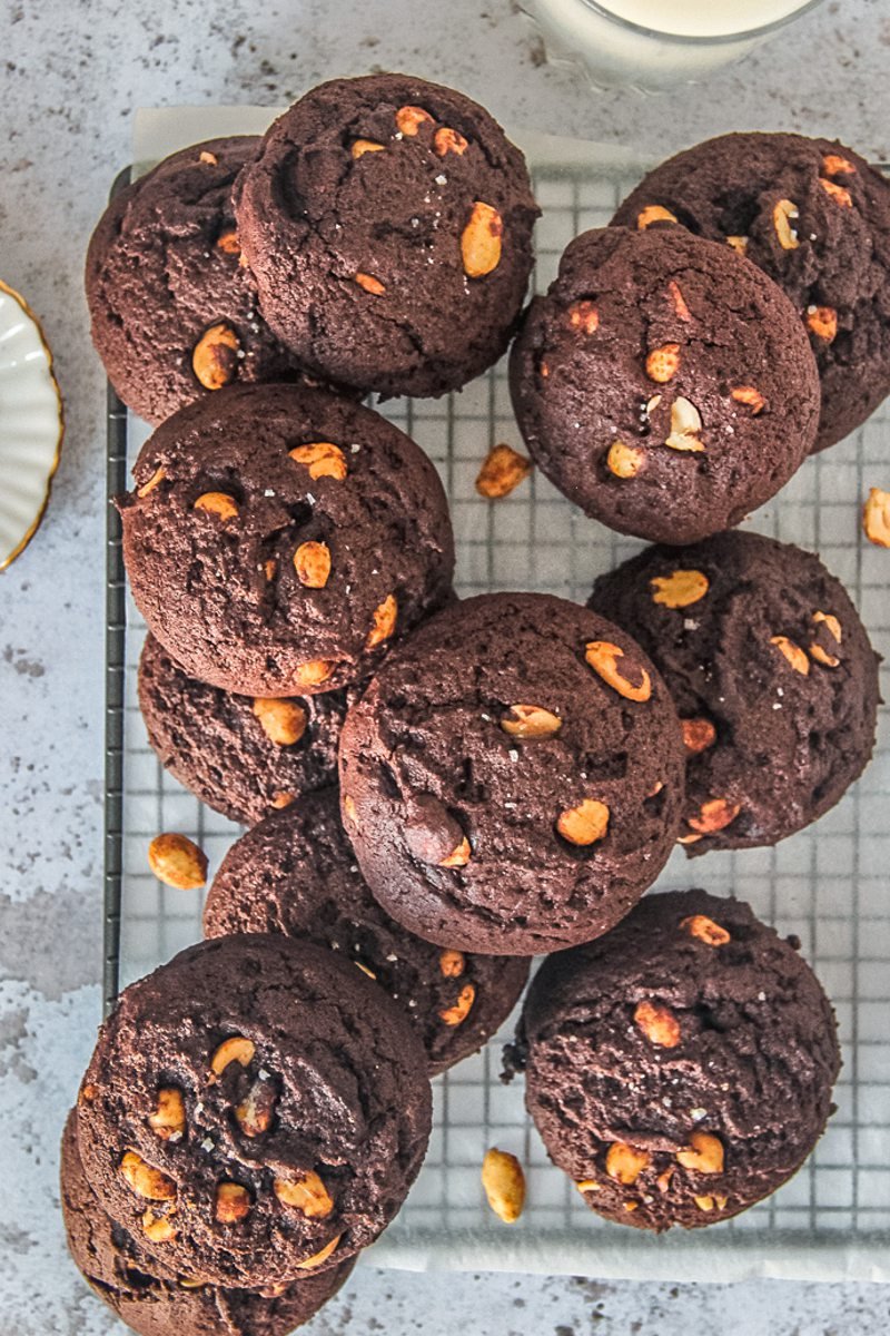 Peanut brownie cookies sit on a cooling rack on a gray surface.