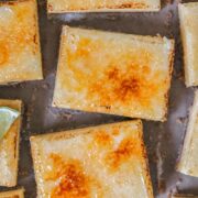 Bruleed key lime bars sit on a gray surface.