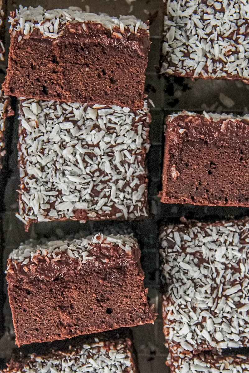 Slices of Swedish Love Cake with the sponge like cake texture and soft chocolate frosting topped with desiccated coconut sit sideways.