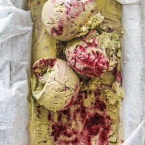 Scoops of matcha blackberry semifreddo sit on top of a tin of semifreddo lined with parchment paper.