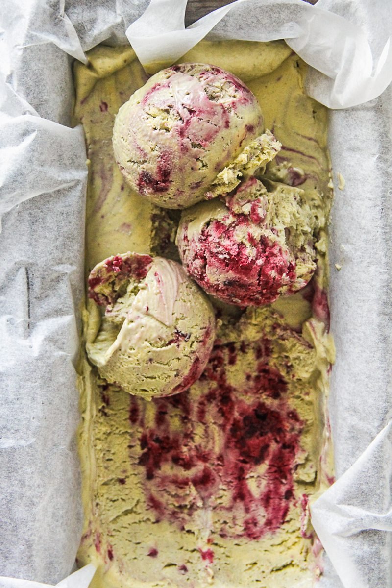 Scoops of matcha blackberry semifreddo sit on top of a tin of semifreddo lined with parchment paper.