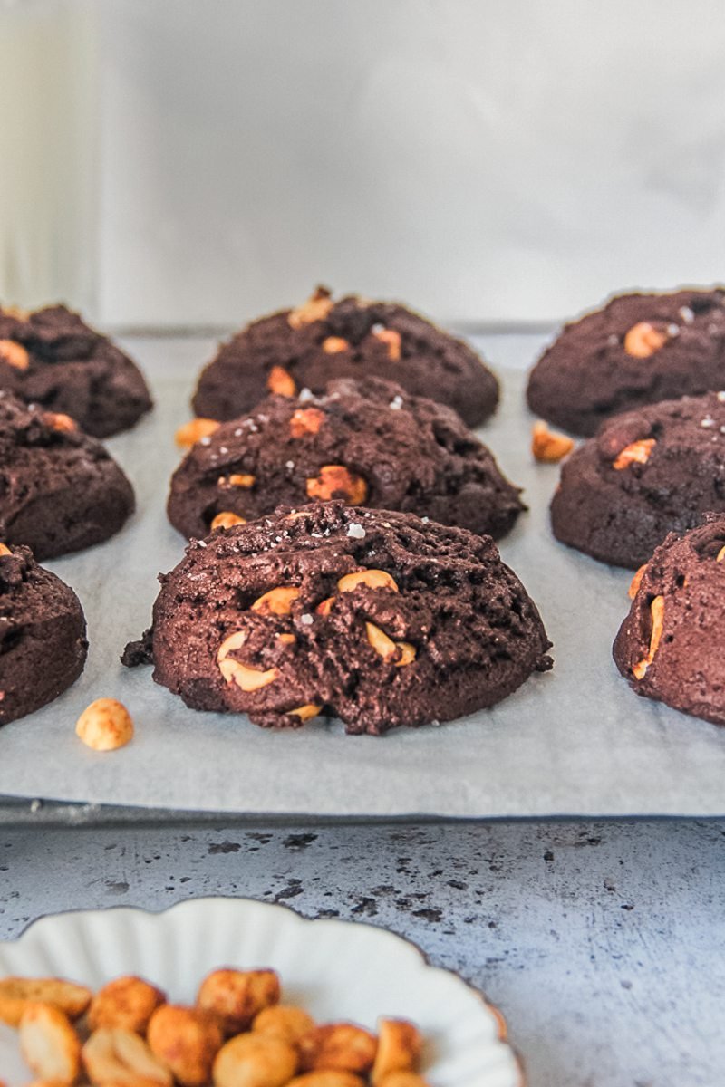 A close up of a peanut brownie cookie sitting on a cooling rack on a gray surface.