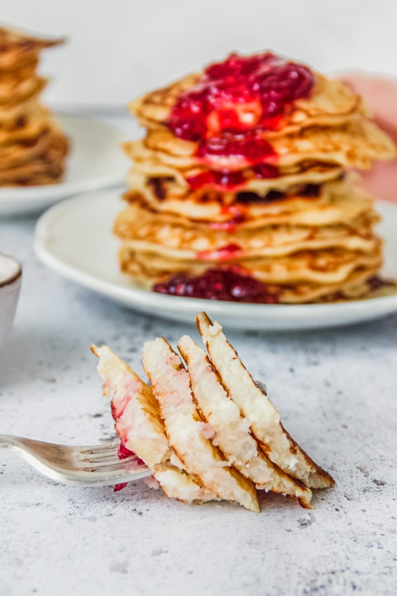 A forkful of rice pudding pancakes rests on a light gray surface.