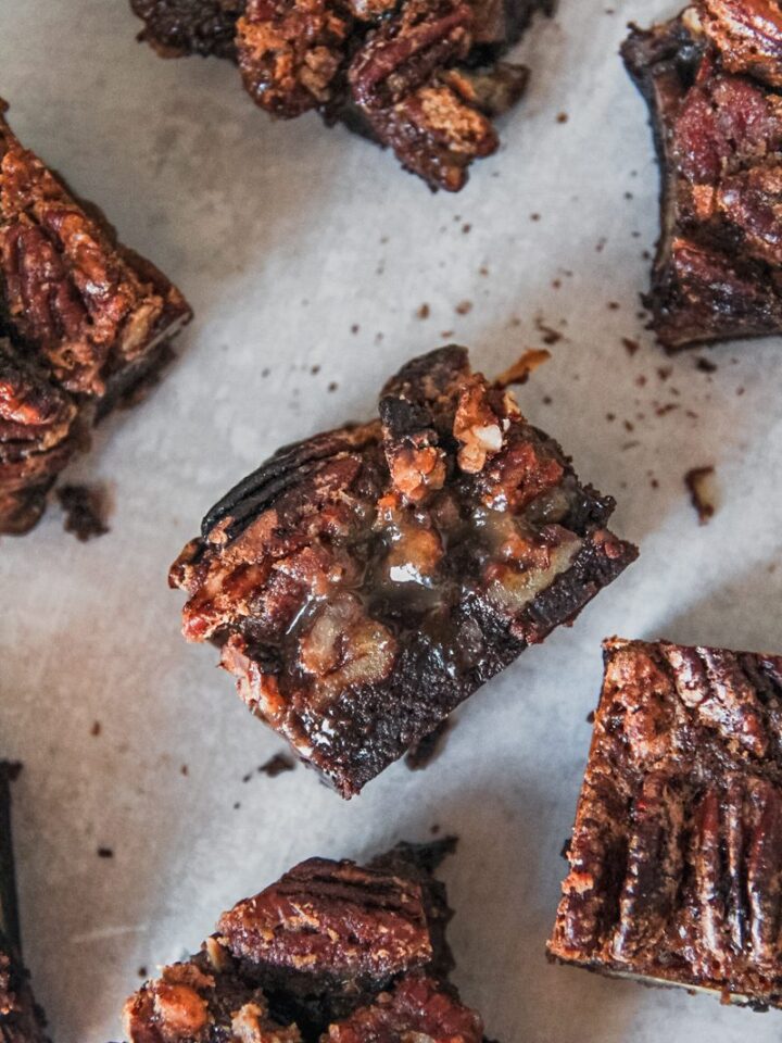 A square of pecan pie brownie sits on it's side with the fudgy and gooey center visible.