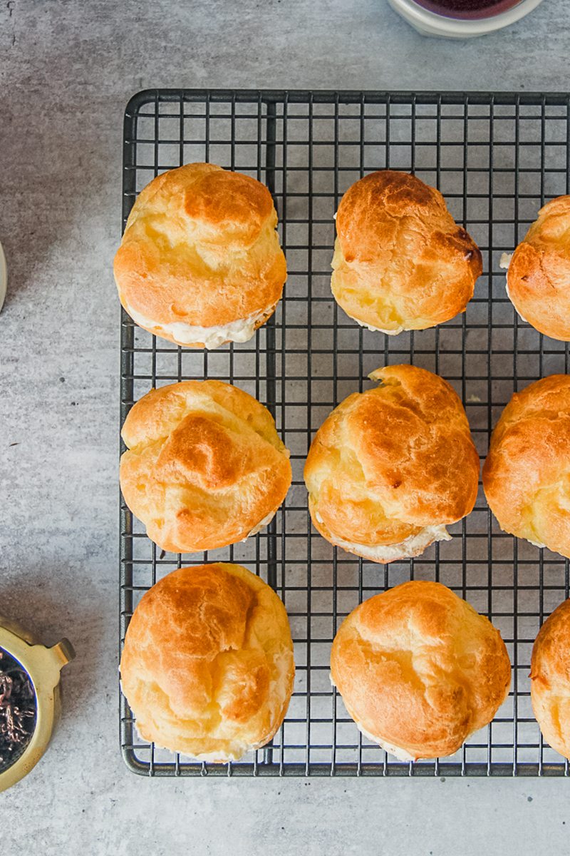 Cream puffs sit on a cooling rack.