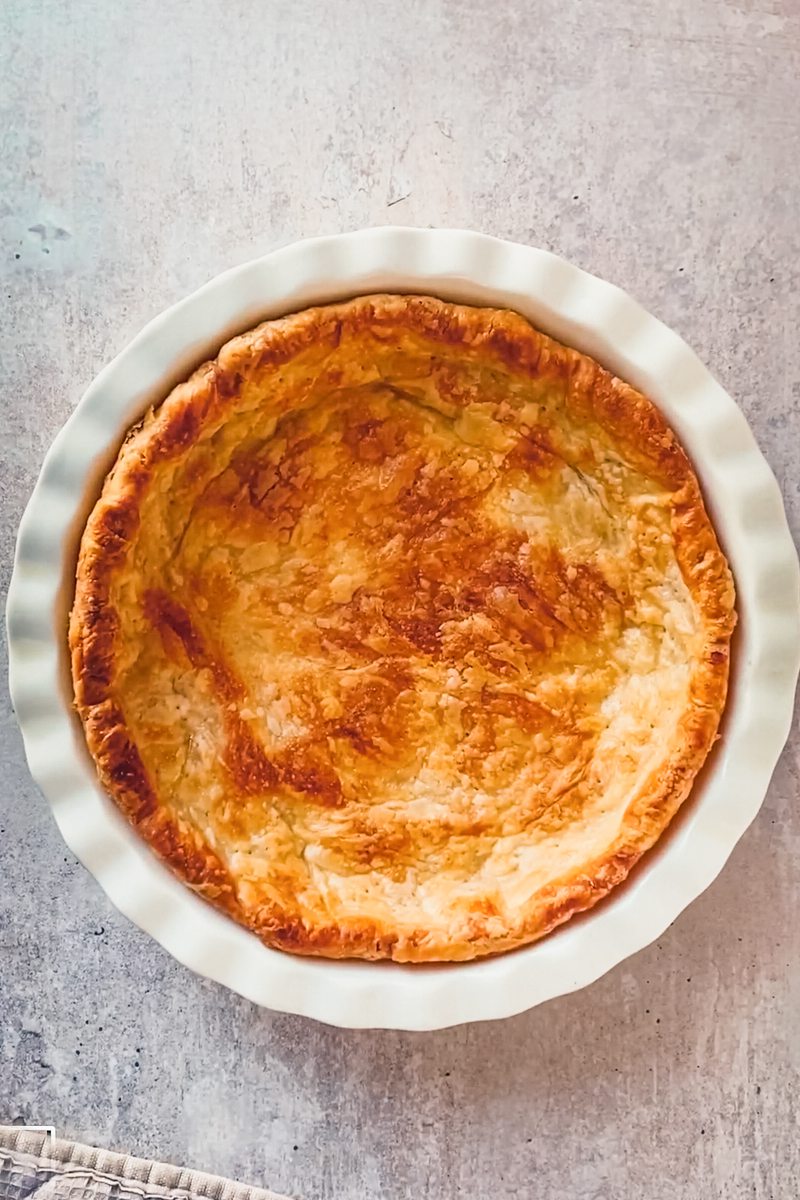 Par baked pie crust sits in a white ceramic baking dish on a gray surface.