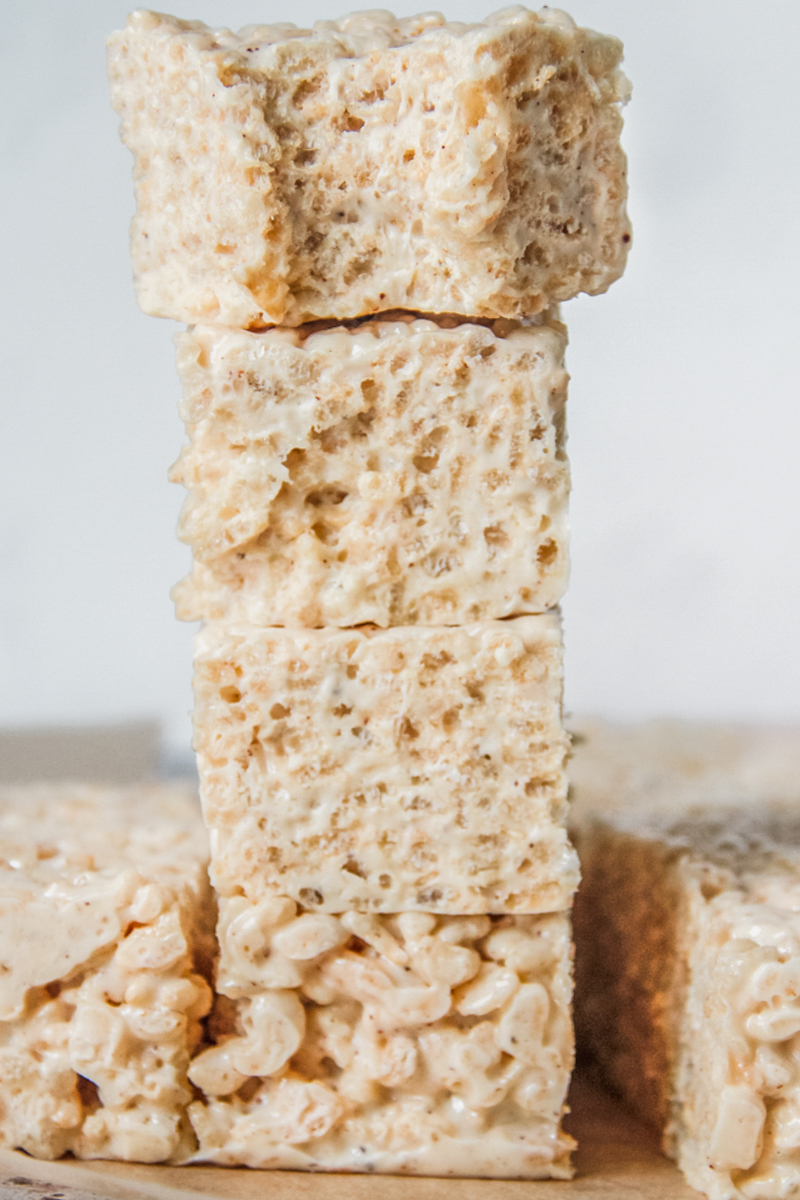 Rice krispie treats sit stacked on each other beside other rice krispie treats.