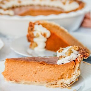 A slice of sweet potato pie has it's close up on an individual plate on a light gray surface.
