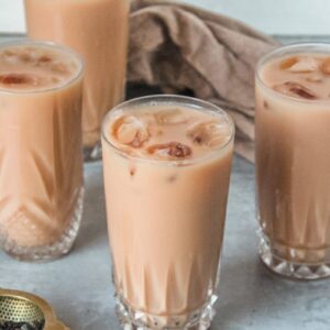 Individual glasses of Thai ice tea sit on a gray surface.