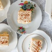 Slices of Tres Leches sit on individual plates on a light gray surface.