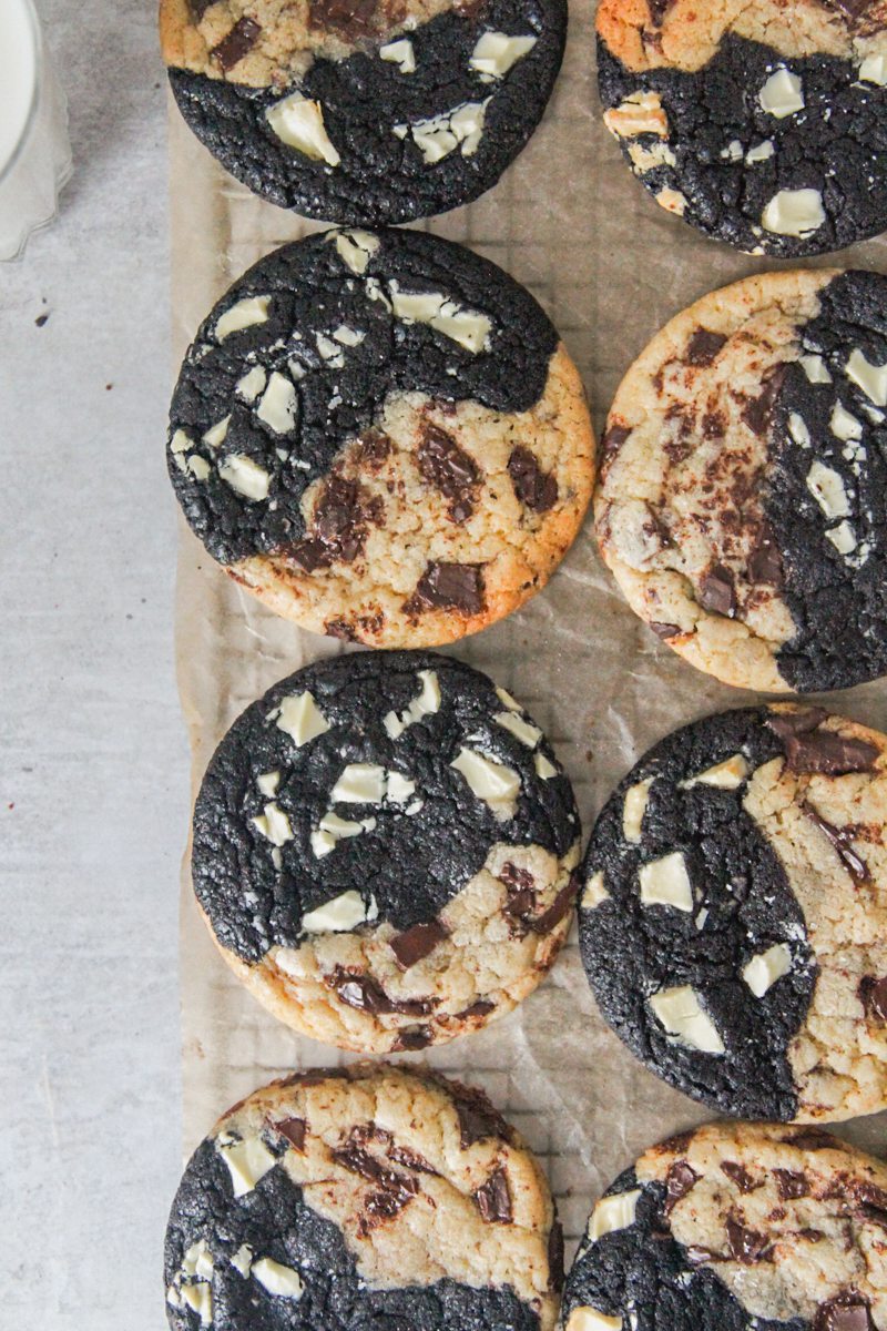 Triple chocolate cookies sit on brown paper on a cooling rack above a gray surface.