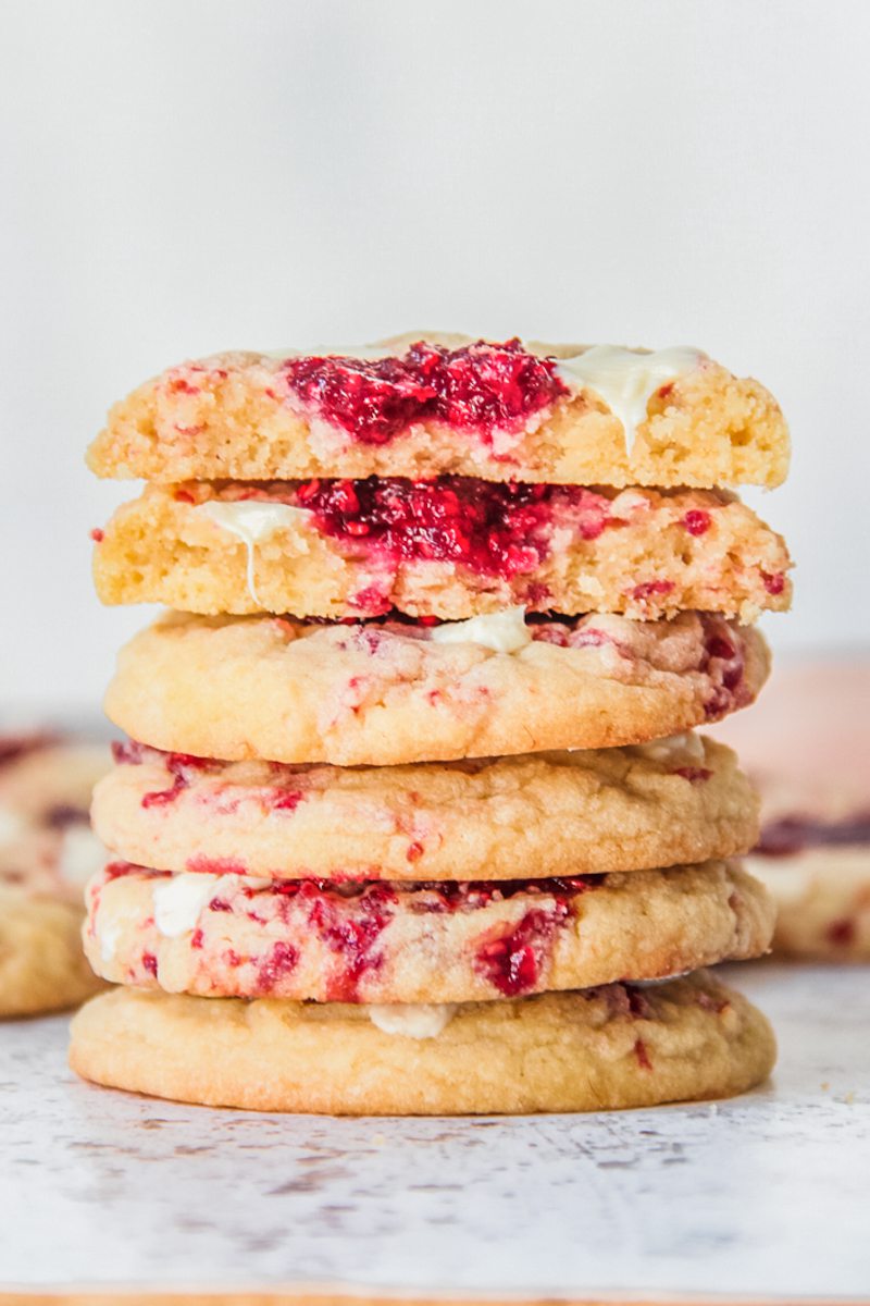 A stack of white chocolate raspberry muffin cookies sit on a light gray surface.
